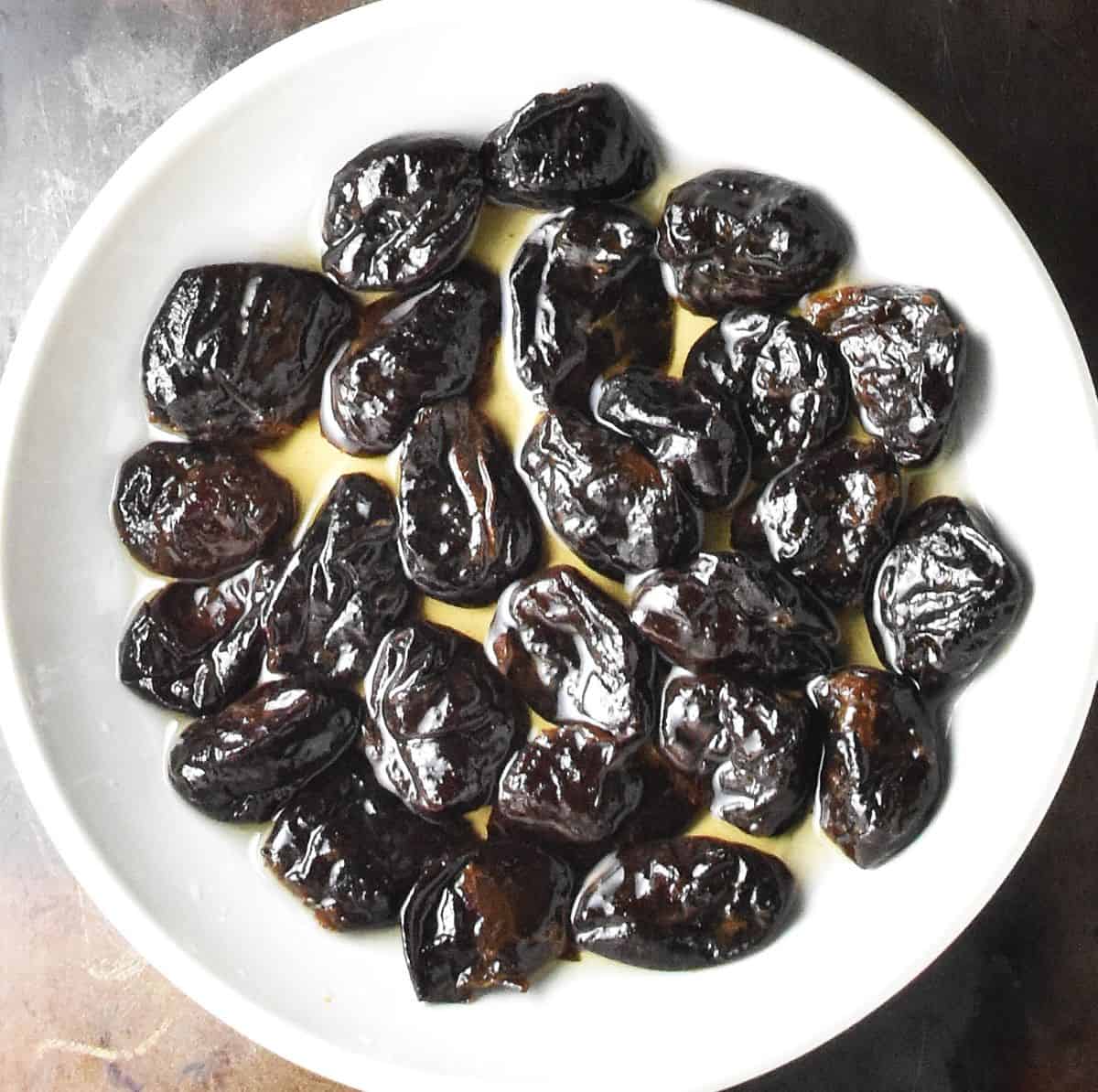 Prunes with alcohol in white bowl.