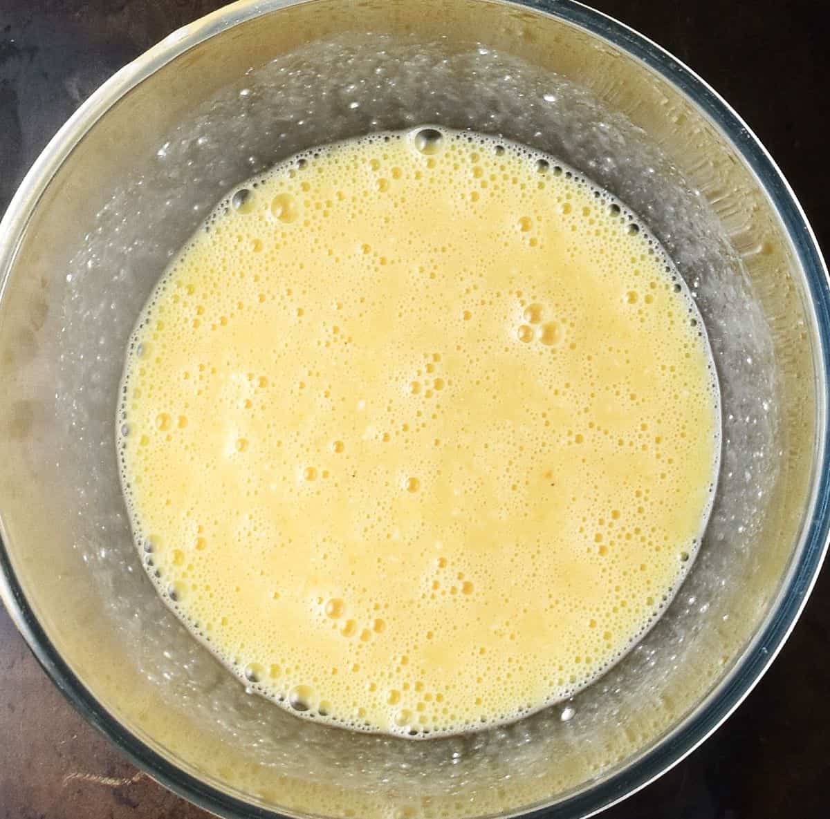 Creamy cottage cheese scrambled egg batter in glass bowl.