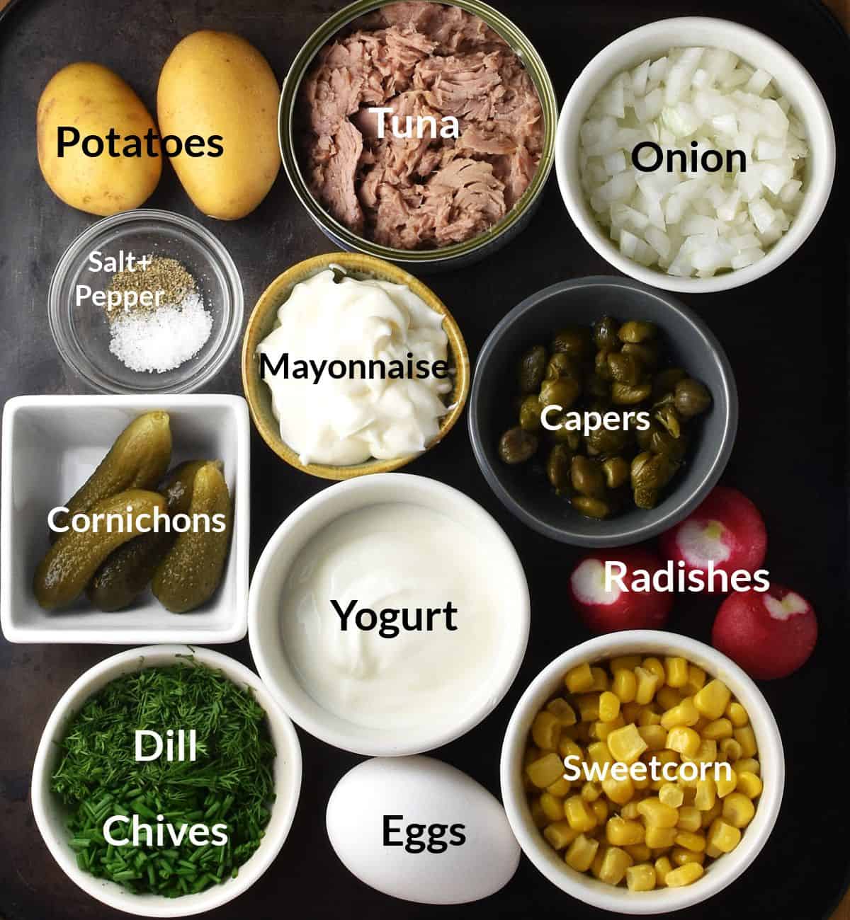 Top down view of potato tuna salad ingredients in individual dishes.