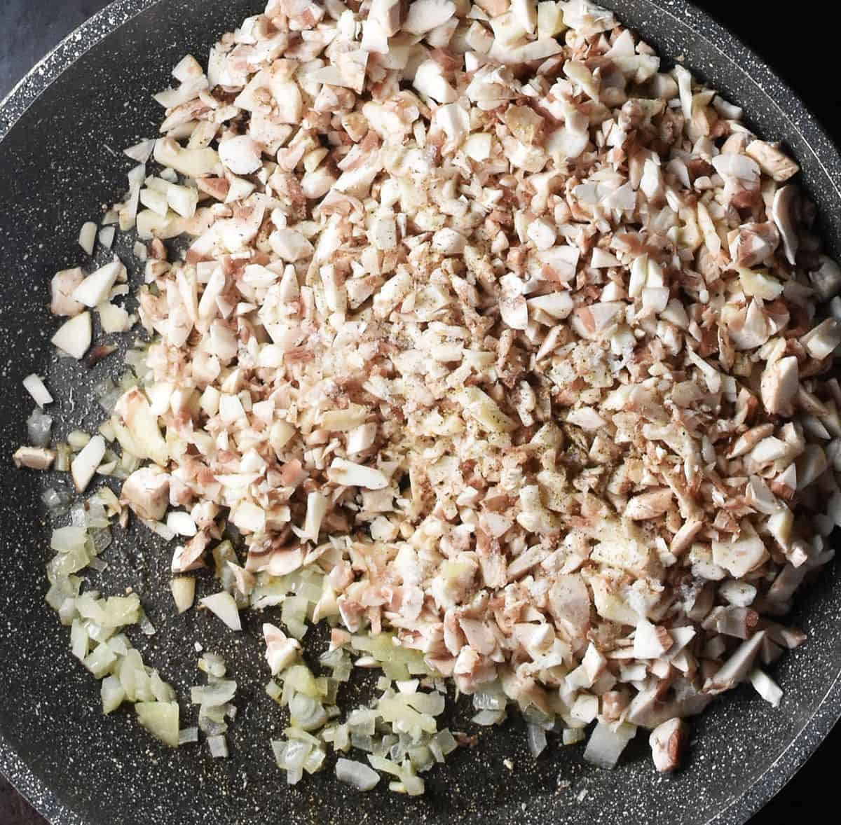 Top down view of finely chopped mushrooms in large pan.