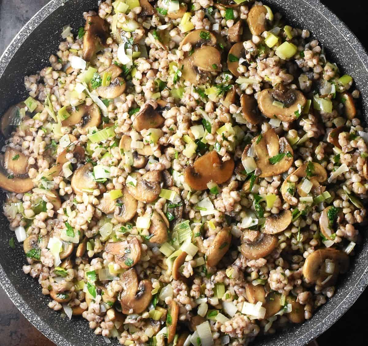 Top down view of mushroom buckwheat with herbs in large pan.