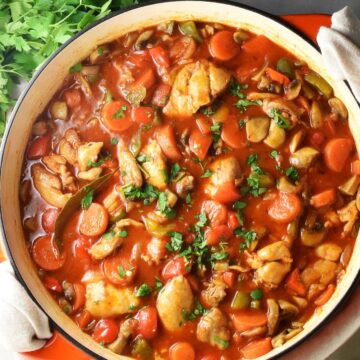 Top down view of chicken goulash in large shallow white pan.