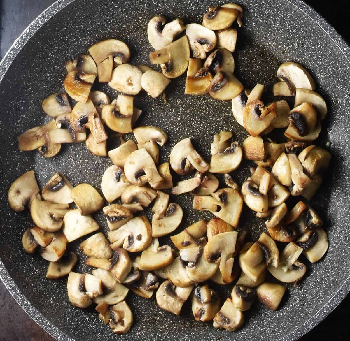 Sauteed sliced mushrooms in large pan.