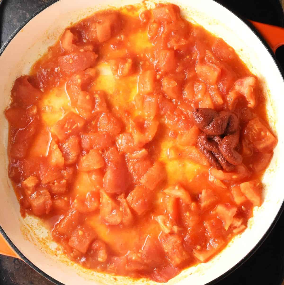 Top down view of stewed tomatoes in shallow white pan.