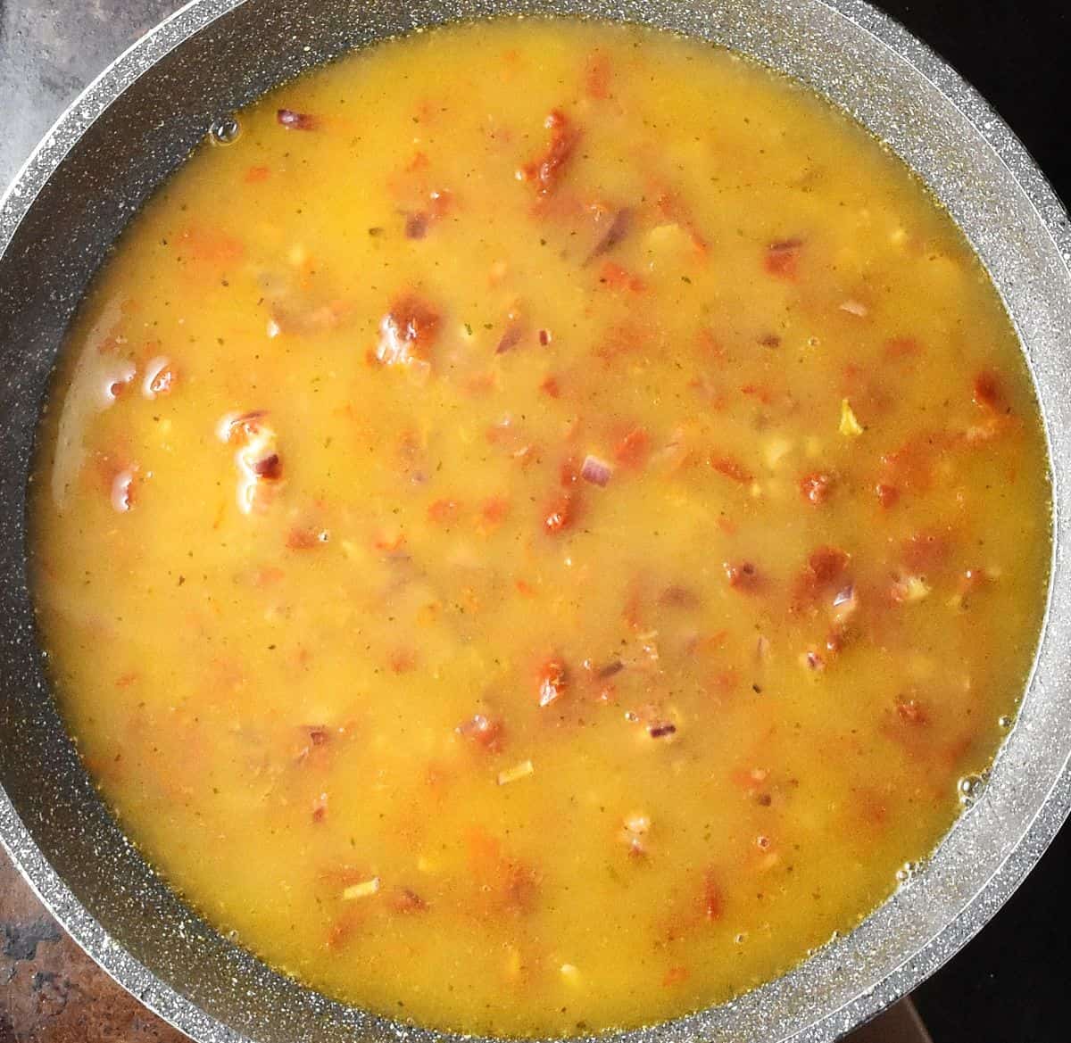 Sun-dried tomato sauce in shallow, large pan.