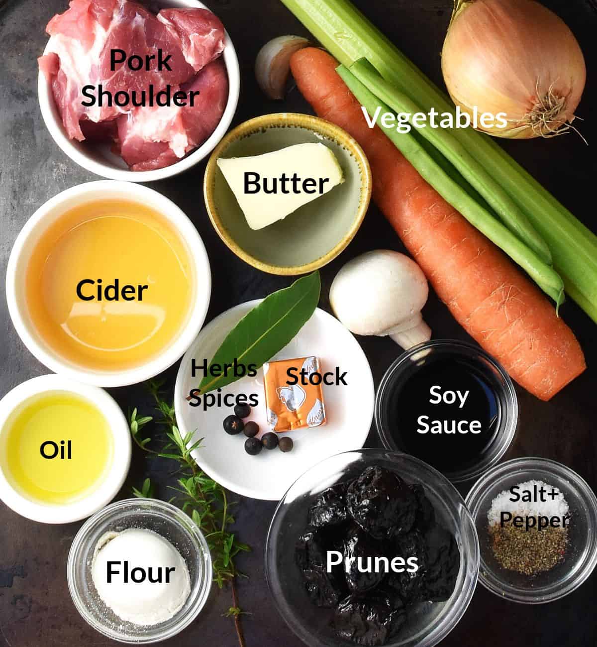 Top down view of pork shoulder stew ingredients in small, labelled dishes.