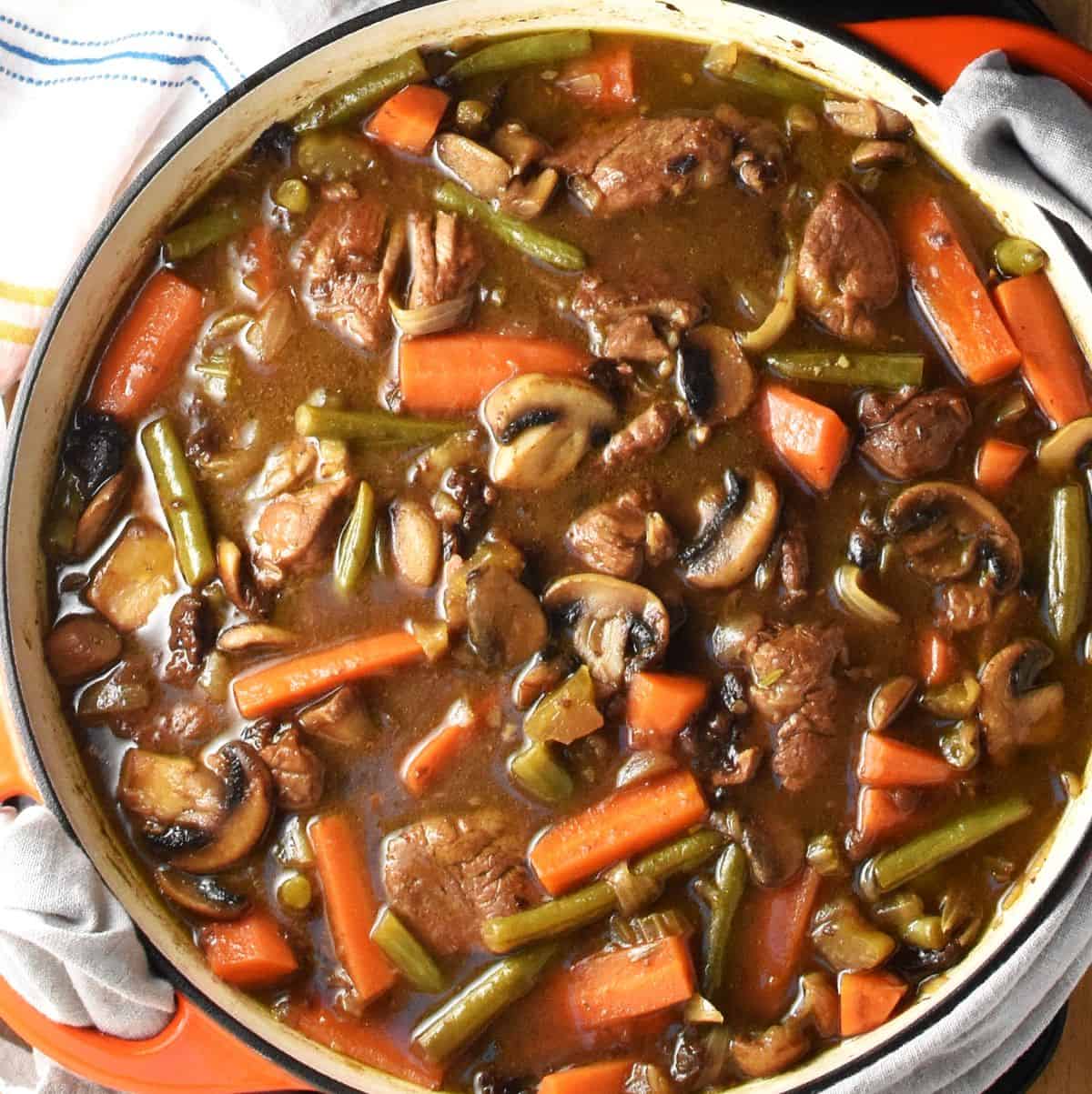 Cooked stew with pork shoulder and vegetables in large shallow pan.